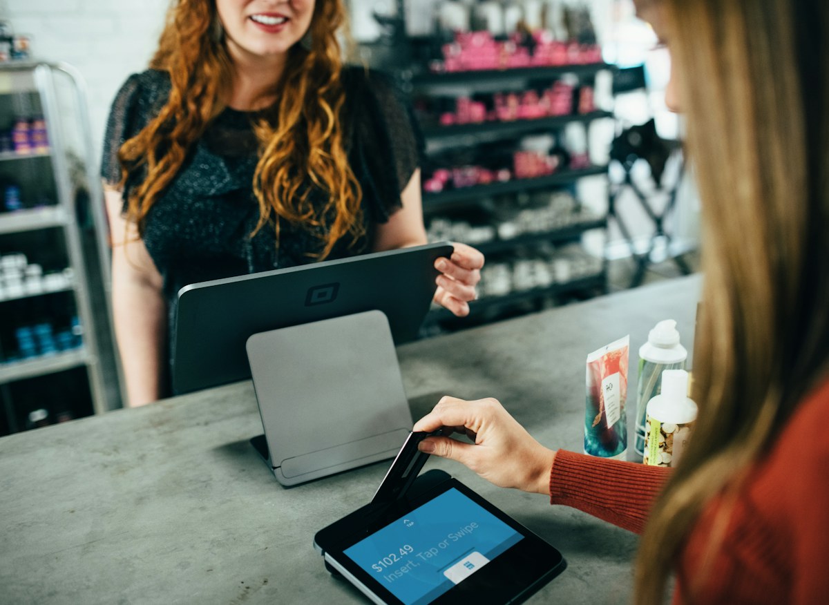 A hand holding a payment card at a shop counter