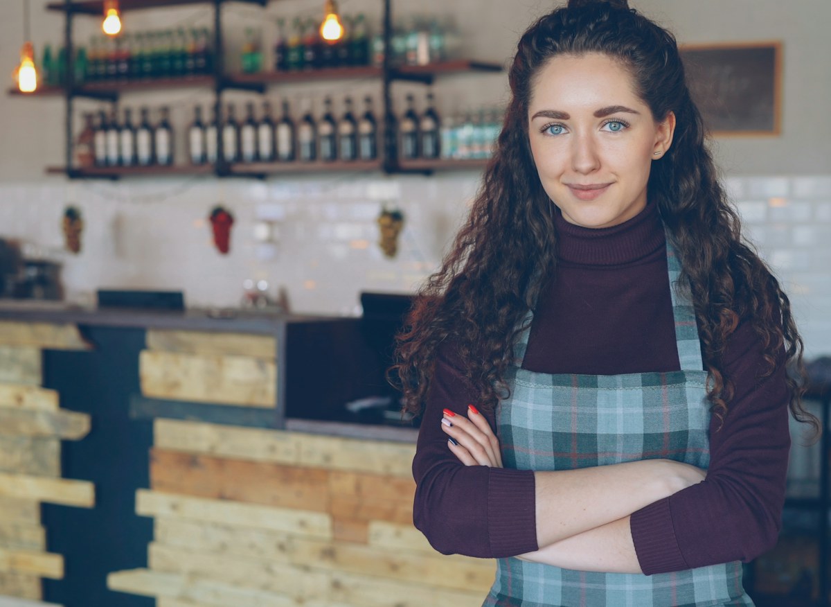 A smiling woman stands in her coffee shop